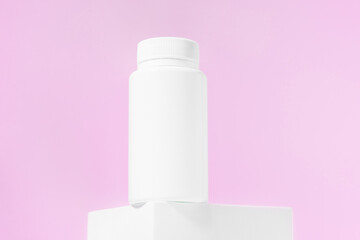 White mockup of a jar of pills or tablets on a pink isolated background. The concept of natural dietary supplements for women's health, pharmacy, vitamins