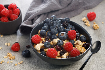 Dry granola with blueberries, raspberries and nuts on grey background . Healthy breakfast meal	
