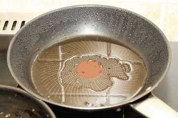 a frying pan with oil is heated on the stove, dirty fat