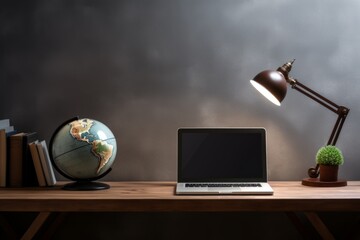 Fototapeta premium Desk with lighted table lamp, laptop, books and a globe