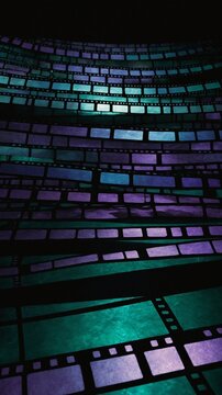 Strips of film negatives curve, twist, creating wave-like pattern against dark background. Negatives illuminated with varying shades of blue, green, purple, giving image ethereal, dreamlike quality.