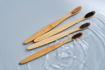 Natural bamboo toothbrushes in water on a blue background.
