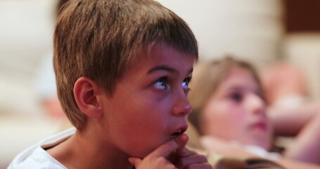 Child seated on sofa in the evening watching movie