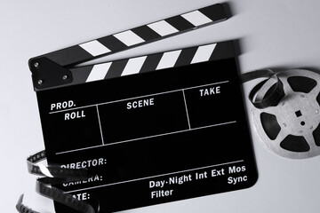 Clapperboard and film reel on grey background, flat lay