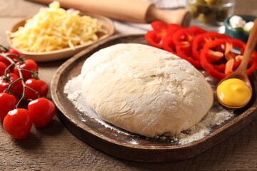 Pizza dough and products on wooden table, closeup