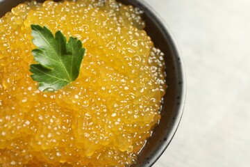 Fresh pike caviar and parsley in bowl on table, closeup