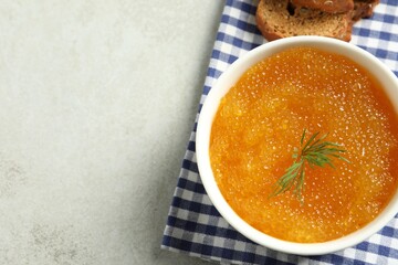 Fresh pike caviar in bowl and bread on light grey table, top view. Space for text