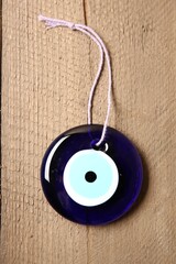 Evil eye amulet on wooden table, top view