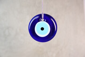 Evil eye amulet hanging on light background, closeup