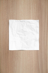 Crumpled white paper on brown wood texture