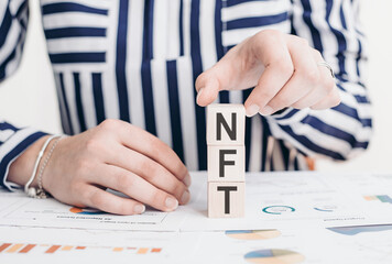 Woman holding cubes with NFT word on the table