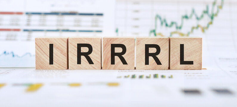 Wooden blocks spell out IRRRl in front of a stock chart, symbolizing the acronym for Interest rate reduction refinance loan.