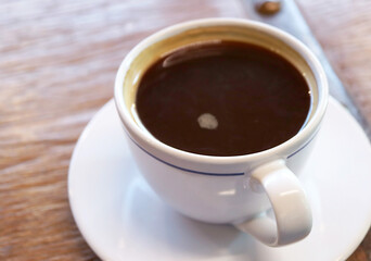 Fototapeta premium Closeup of a cup of black coffee isolated on wooden table