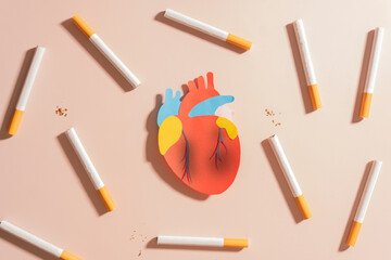 Smoking damages heart and blood vessels. Cigarettes or tobacco with unhealthy human heart organ on...