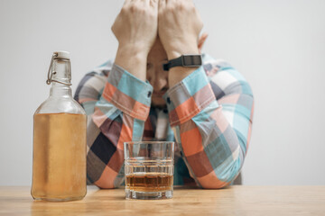 Addicted and drunk man at the table with a glass of alcohol drink, whiskey or brandy, alcoholism...