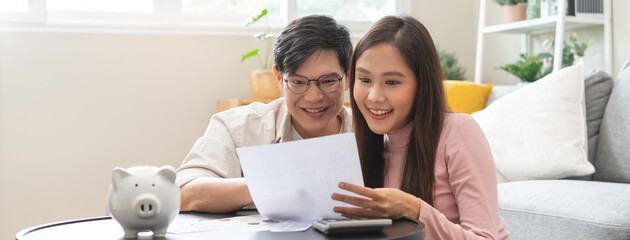 Happy asian family young couple love hand holding piggy bank to save and model house for saving money wealth to buy real estate for new home. Financial planning, business finance concept. Housing loan