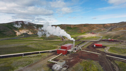 Geothermal power station in Icelandic landscape, steaming chimneys in the valley on a bright sunny...