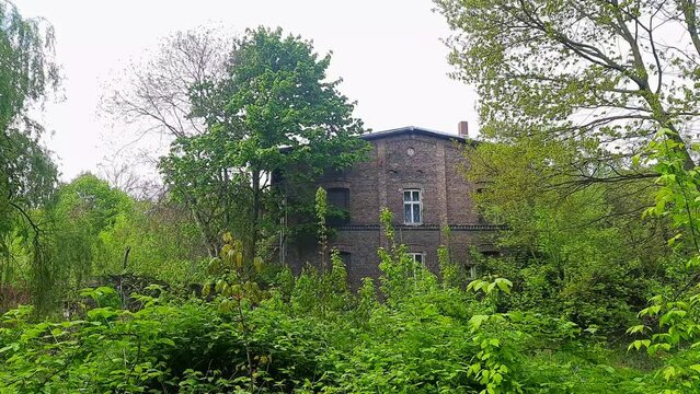 Old brick house among the trees. Lonely building in abandoned park. House with ghosts.