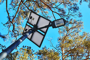 view from below of a street lamp and a solar panel on a pole