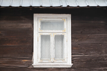 Wooden rustic window in cottage house. Rusty architecture. Podlasie region in Poland vintage wall. Wood home wall facade. Metal sheet corrugated roof. Village farm building. Lace  curtain interior.