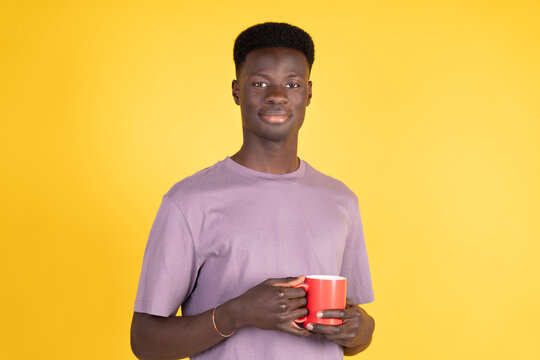 A man with a red mug in his hand is smiling at the camera