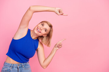 Portrait of nice young girl indicate fingers empty space wear blue top isolated on pink color...