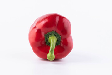 A red pepper lies with the green stalk down on a white background.