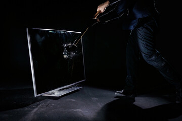 Man holding a sledgehammer, hitting and smashing a plasma television, isolated on a black background, slow motion locked down shot. People and technology concepts.