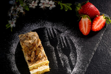 Norwegian cake. With meringue, whipped cream and almonds. Dark background