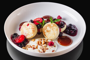 cottage cheese pancakes with berries and jam on a white plate