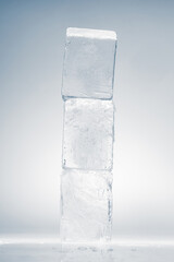 Cubes of natural textured clear ice on a white reflective surface. Ice background.