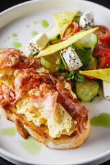 toast with scramble and bacon on a white plate