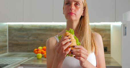 Woman eating croissant sandwich with lattice and bacon