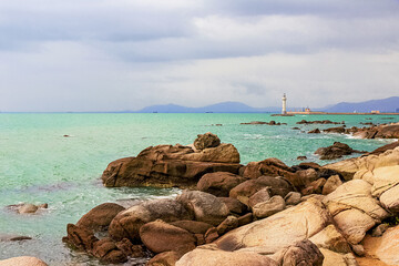 View of the lighthouse in the sea near the rocky shore. Heavenly Grottoes Park, Sanya, China