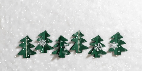 Minimal pattern of Green Christmas trees cut out of paper on white fur with snow, winter holidays background. Handmade green tree firs decorated snowflakes, pearls. Aesthetic top view, xmas