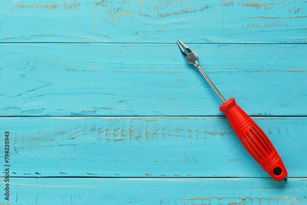 Wall mural A red screwdriver placed on a blue wooden table. Suitable for DIY and construction projects