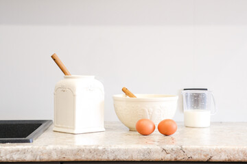 Home kitchen interiorBowl with dough, milk, eggs and bowl of sugar on kitchen table in modern kitchen.