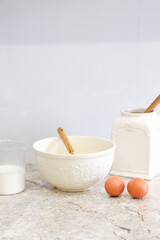 Home kitchen interiorBowl with dough, milk, eggs and bowl of sugar on kitchen table in modern kitchen.