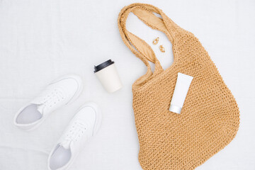 Straw bag for beach, glass of coffee, tube of lotion on white background. Summer and beach accessories.