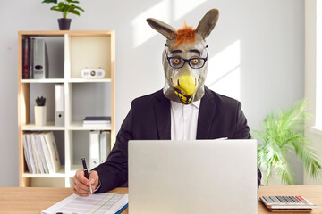 Corporate financial accountant in funny animal mask working in office. Man employee in unusual,...