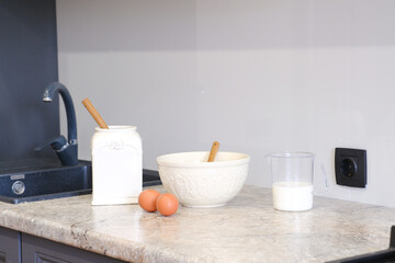 Home kitchen interiorBowl with dough, milk, eggs and bowl of sugar on kitchen table in modern kitchen.