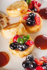 cottage cheese pancakes with berries and jam on a white plate