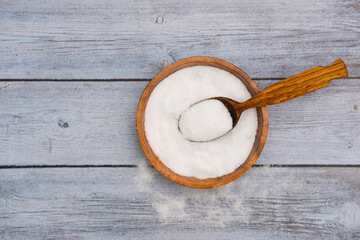 Pure natural sea salt in wooden bowl and wooden spoon isolated on grey background.