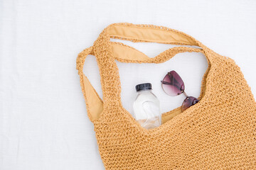Straw bag for beach, bottle of water and sunglasses on white background. Summer and beach accessories.
