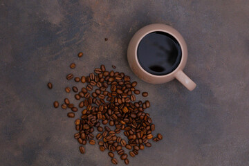 Cup glass of coffee and coffee beans on dark brown background.