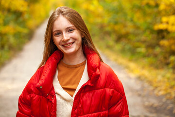 Portrait of a young beautiful red hair girl in autumn park