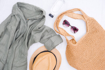  Look of women for spring summer. Linen shirt, Straw bag for beach, bottle of water, straw hat and sunglasses on white background. Summer and beach accessories.