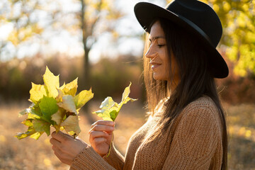Beautiful woman with autumn leaves on fall nature and sun background