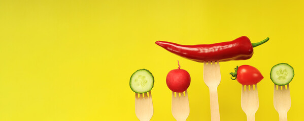 Pepper, tomato, cucumber and radish on wooden disposable forks, close-up, yellow background. Healthy eating concept. Fresh vegetables in the diet. Vegetables on a black background. Space for text