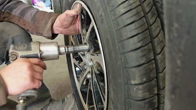 Mechanic tightens bolts on a wheel